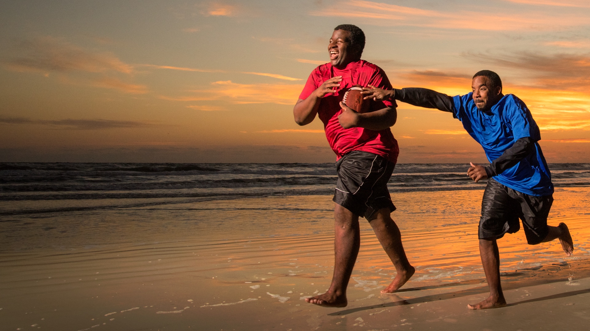 Two kids playing football on the beach